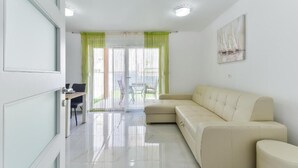 A modern living room with a beige sofa, a dining table with chairs, and a glass door leading to an outdoor area. - Cascade villas with private garden and jacuzzi (Starigrad)
