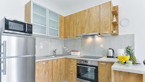 A modern kitchen with wooden cabinets, stainless steel appliances, and a small countertop area with a kettle and fruit. - Cascade villas with private garden and jacuzzi (Starigrad)