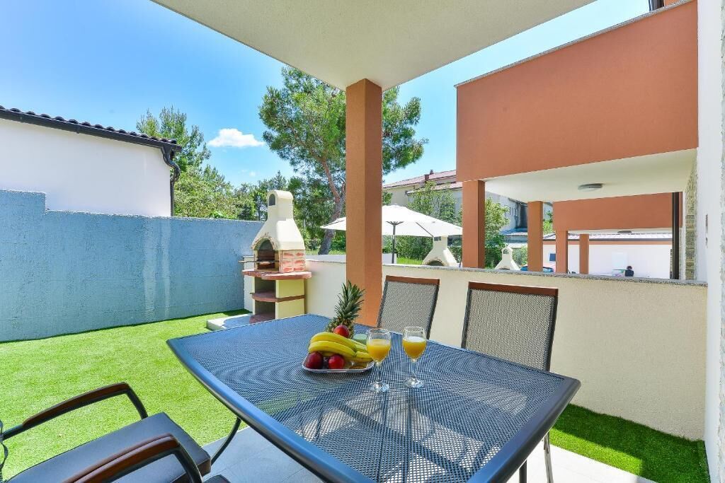 Une terrasse extérieure avec une table dressée pour deux personnes, un barbecue et une vue sur les environs.
