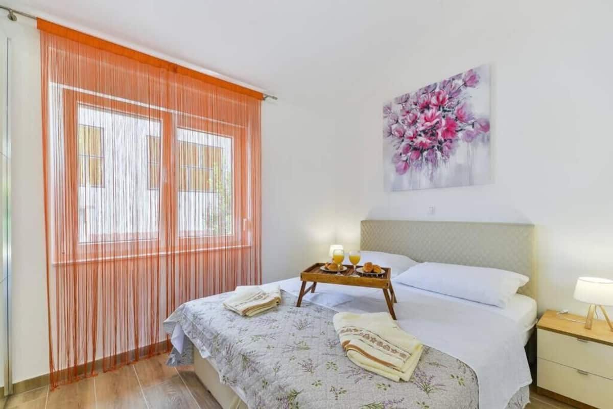 A neatly made bed with a floral bedspread, a bedside table with a lamp, and a breakfast tray on the bed.