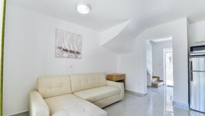 A modern living room with a beige sectional sofa, a wooden side table, and a painting of sailboats on the wall. - Cascade villas with private garden and jacuzzi (Starigrad)