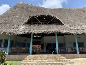 A building with a thatched roof, a covered porch, and a stone staircase leading to the entrance. - Wonderful area as described. Feel at home. (Malindi)