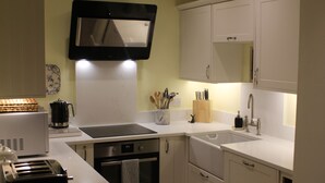Een moderne keuken met witte kasten, een ingebouwde magnetron en een RVS-spoelbak.