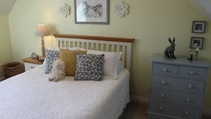 Een slaapkamer met een bed, een dressoir, een lamp en decoratie aan de muur.