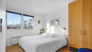 Un dormitorio con cama, armario, ventana y radiador.