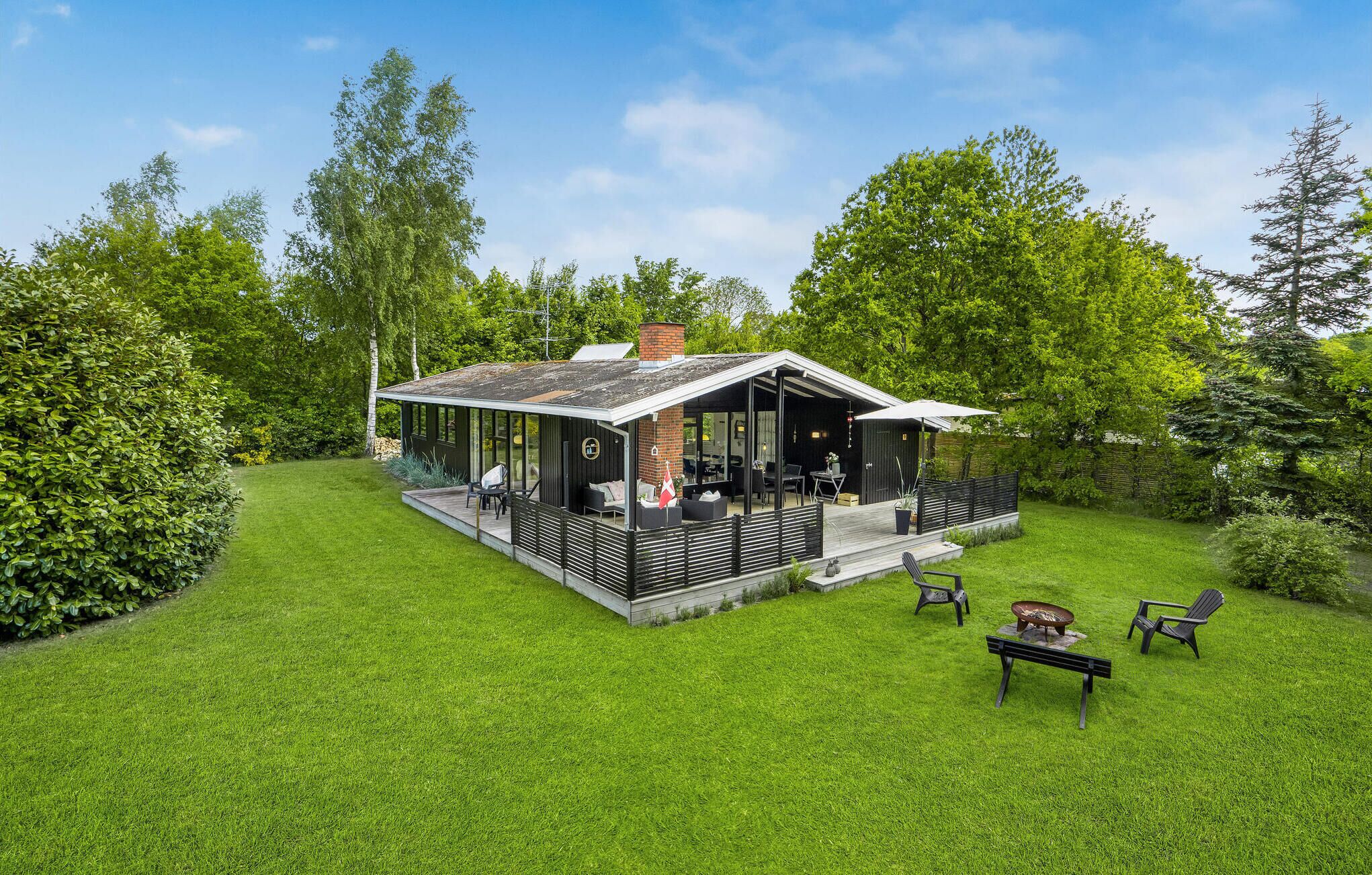 Una casa moderna con un porche cubierto, una terraza y un césped bien cuidado.