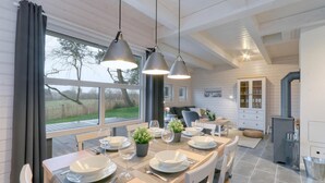A modern kitchen with a dining area, featuring a large table set for six, pendant lighting, and a view of the outdoors. - Lovely home in Krems II/Warderbrück with sauna (Krems II/Warderbrück)