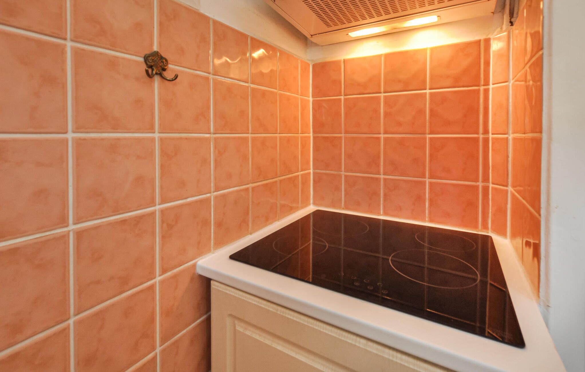 Une cuisine avec des carreaux orange, un fourneau et une hotte aspirante.