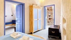 Una habitación con cama, armario de madera, cómoda y pared de piedra.