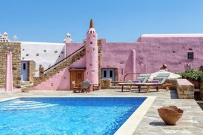 Un espace piscine agrémenté d’un mur en pierre, d’un bâtiment rose et d’un escalier.