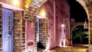 Un arco de piedra que da paso a un edificio de fachada rosa y suelo de piedra.
