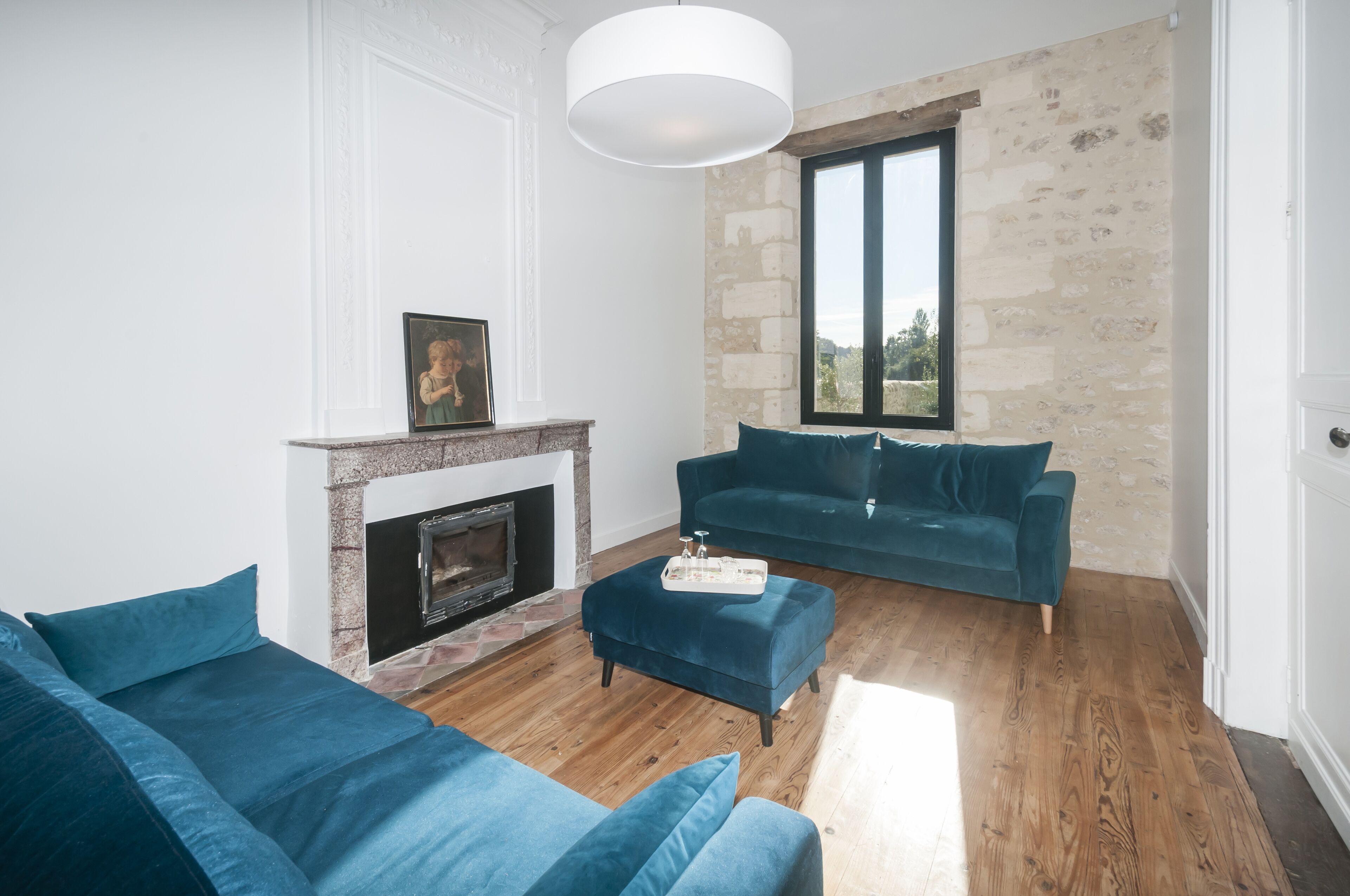 A living room with a fireplace, a blue sofa, and a stone wall.