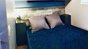 Ein Schlafzimmer mit einem Bett, zwei Nachttischen und einem an geometrischen Mustern verzierten Kopfteil.
