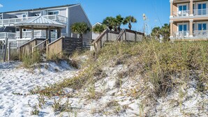 A beachfront property with a wooden deck, a covered area, and a building with balconies. - Summer Retreat - Prime Location | Sleeps 8 | Pets (Destin)