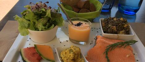 A meal tray with salmon, watermelon, a bowl of salad, a glass of smoothie, and a bowl of lentils.