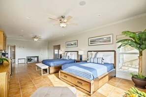 A bedroom with two beds, a ceiling fan, a large window, and a potted plant. - Casa de la Perla ☀️ Boat Parking, Ocean View, Elevator & Beach Boardwalk | Pet Friendly (Port Aransas)