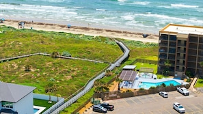 A coastal hotel with a swimming pool, a parking area, and a beach view. - Casa de la Perla ☀️ Boat Parking, Ocean View, Elevator & Beach Boardwalk | Pet Friendly (Port Aransas)