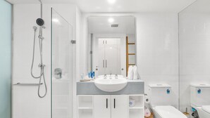 A modern bathroom with a glass-enclosed shower, a large sink, and a toilet. - Beach Club Top Floor Oceanfront Studio Palm Cove (Palm Cove)
