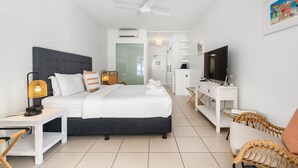 A modern hotel room with a large bed, a TV, a desk, and a chair. - Beach Club Top Floor Oceanfront Studio Palm Cove (Palm Cove)
