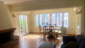 Ein geräumiges Wohnzimmer mit Kamin, einem Esstisch mit Stühlen und einer Couch.