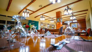 A restaurant with wooden beams, chandeliers, and tables set for dining. - Marina Wadi Degla Hotel (Ataqah)