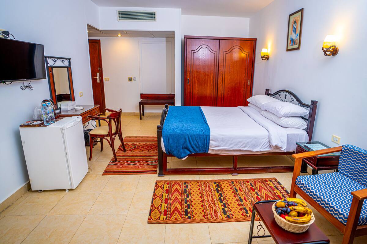 Hotelkamer met een bed, bureau, stoel, kledingkast, televisie en een wandlamp.