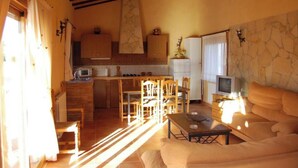 Un saló agradable amb un sofà, una televisió i una zona de menjador amb cadires i una taula.