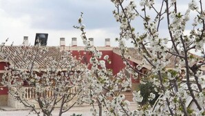 Un edifici amb façana vermella i teulada de rajoles, envoltat d'arbres en flor.