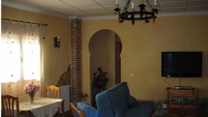 A living room with a television, a dining table with chairs, a sofa, and a chandelier. - 4 bedroom house (Caravaca de la Cruz)