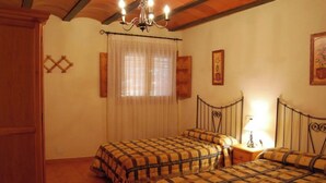 A bedroom with two beds, a chandelier, and a window with curtains. - 4 bedroom house (Caravaca de la Cruz)