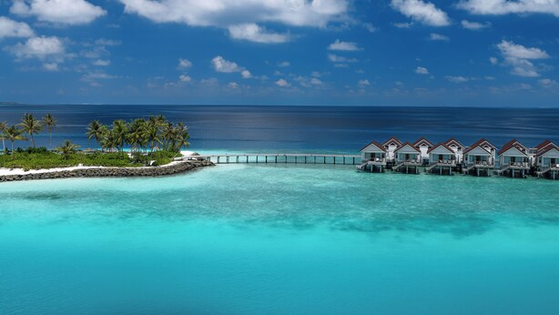 A tropical resort with overwater bungalows connected by a bridge, clear turquoise waters, and palm trees. - OBLU SELECT Lobigili  with Free Transfers (Lobigili)