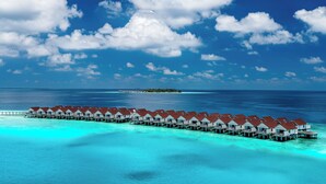 Overwater bungalows with multiple rooms, connected by walkways, and a clear view of the ocean and a distant island. - OBLU SELECT Lobigili  with Free Transfers (Lobigili)