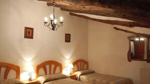 Une chambre avec deux lits, un lustre et un miroir au mur.