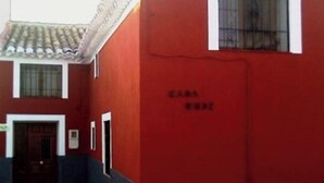 Un bâtiment à la façade rouge et doté d’une petite fenêtre grillagée.