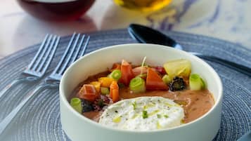 A bowl of soup with vegetables and a dollop of cream on a textured placemat.