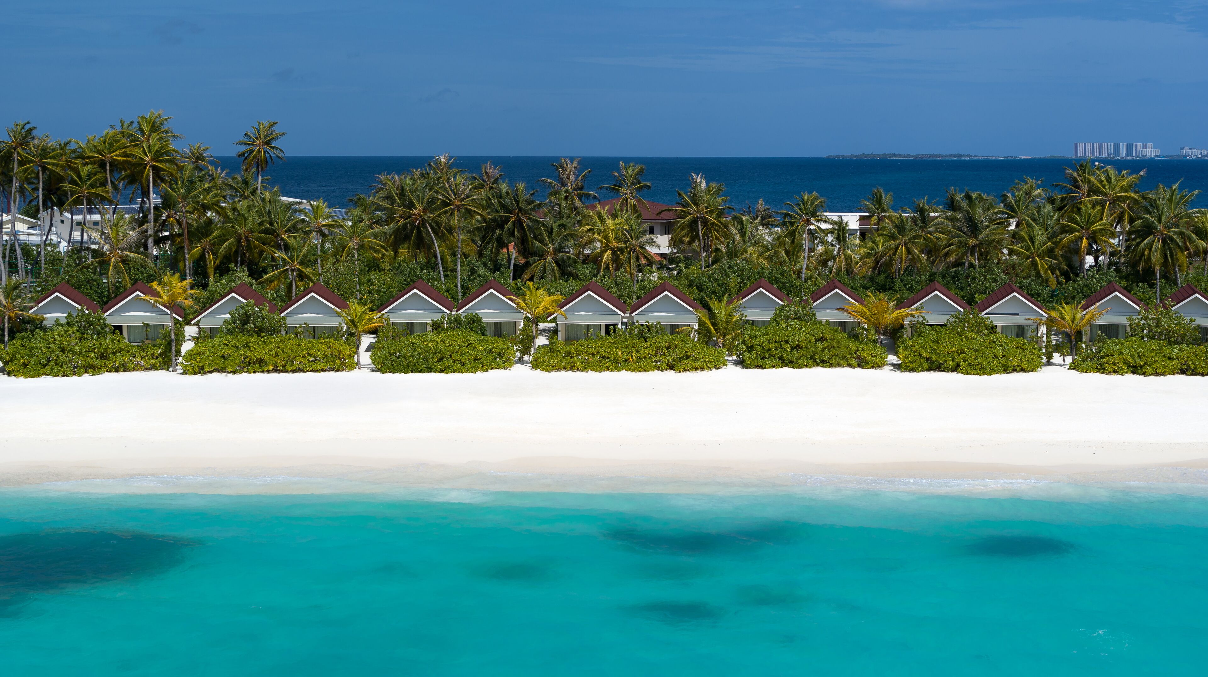 A beachfront resort with overwater bungalows, clear turquoise waters, and a view of the ocean.