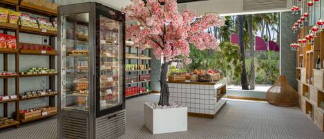 A modern interior with a refrigerated display, a central tree, and shelves stocked with snacks.