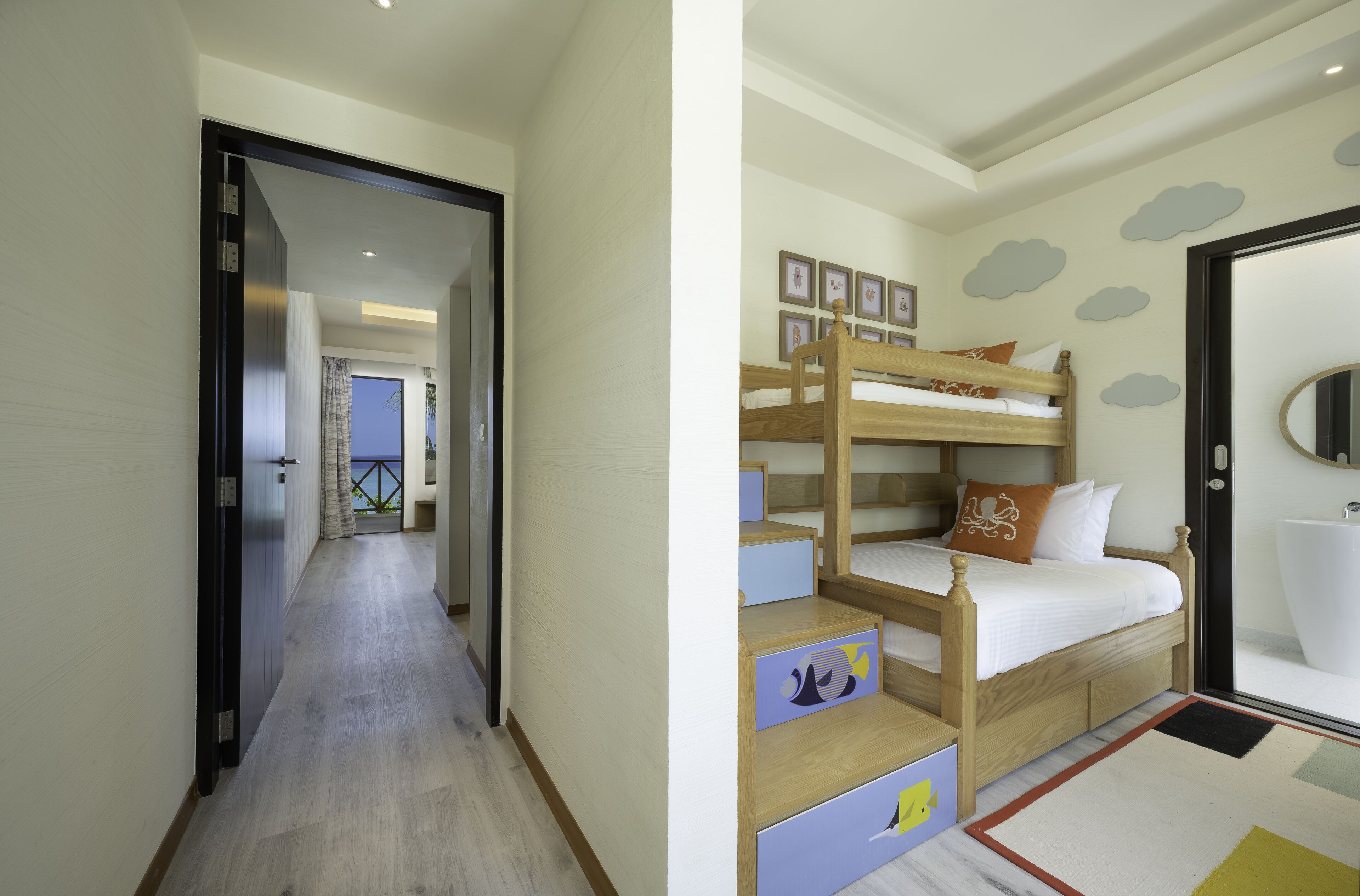 A hotel room with a wooden bunk bed, a small desk, and a bathroom with a large mirror.
