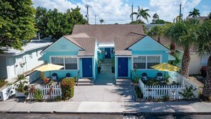 A two-story building with a central entrance, a white picket fence, and a paved driveway.
