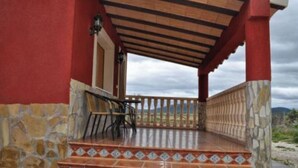 Un espace extérieur abrité, doté d’un sol en pierre et en carrelage, d’escaliers en bois et offrant une vue sur le paysage.