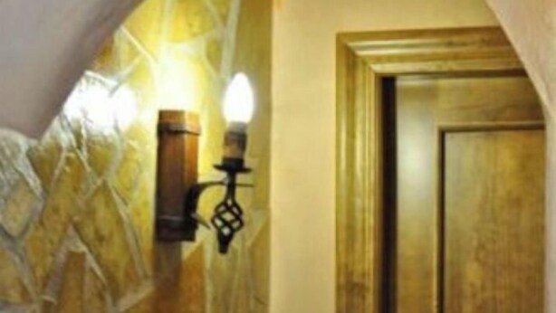 Un mur en pierre avec une porte en bois et un luminaire fixé au mur.