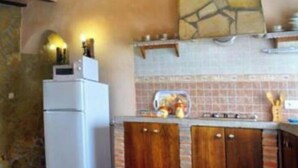 Une cuisine avec un mur d’accent en pierre, des armoires en bois et un réfrigérateur blanc.