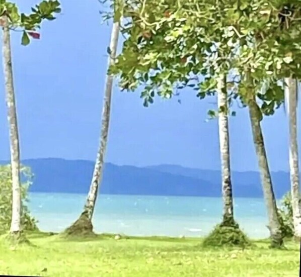 En strand med kristallklart blått vatten och avlägsna berg.