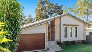 A single-story house with a garage, brick foundation, and a small front yard.