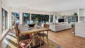 A spacious living area with a dining table, sofas, and a kitchen area.