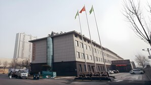 A modern building with a large sign, multiple flags, and parked cars. - Greentree Eastern Hotel Binzhou Zhonghai International Convention and Exhibition Center (Binzhou)
