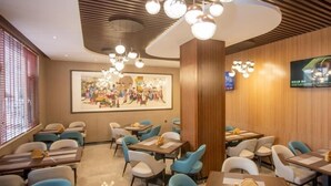 A restaurant with multiple tables and chairs, a large painting on the wall, and a television screen. - Greentree Eastern Hotel Binzhou Zhonghai International Convention and Exhibition Center (Binzhou)