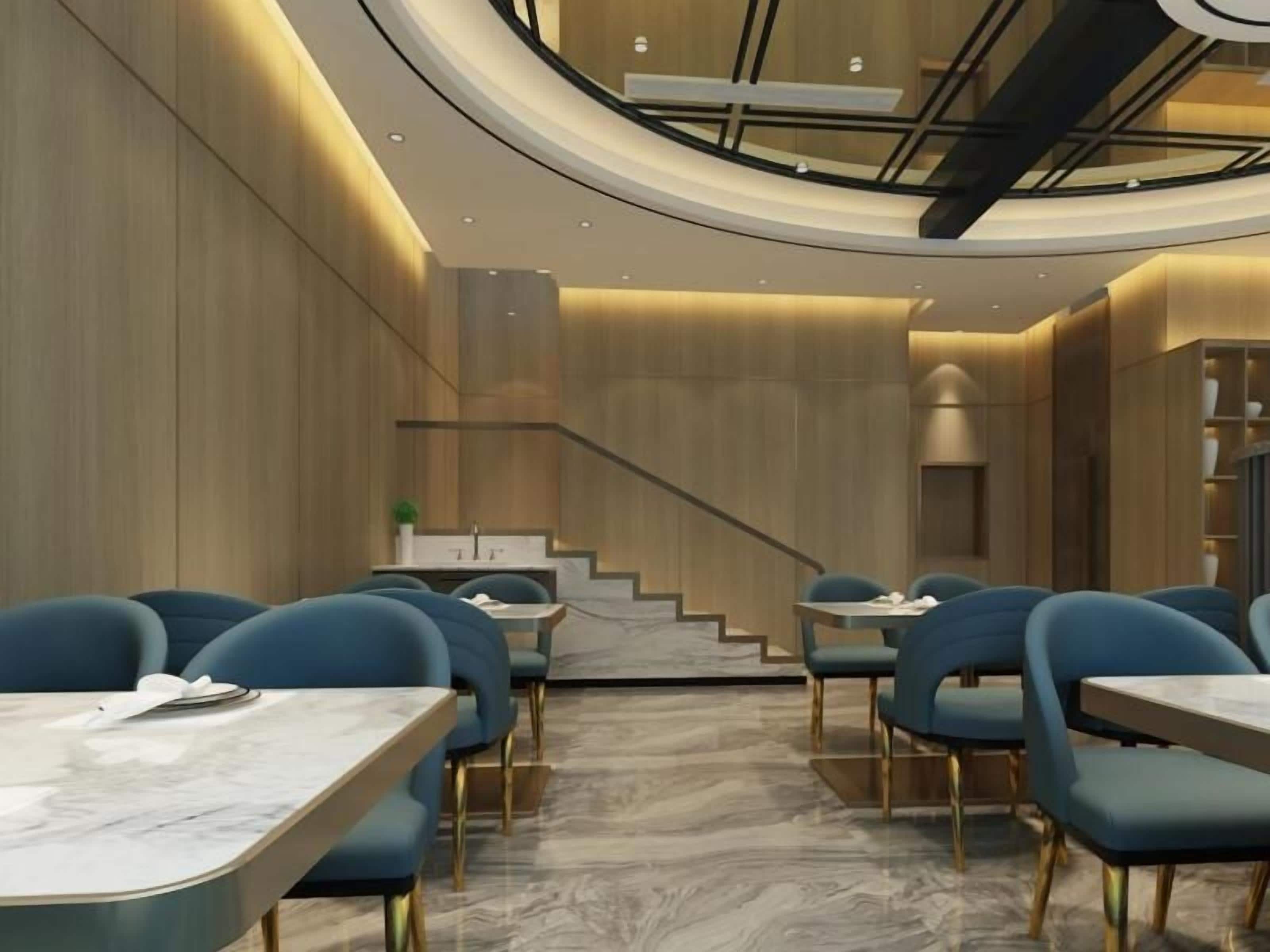 Un interior de restaurante moderno con mesas de mármol, sillas azules, paneles de madera y una escalera.