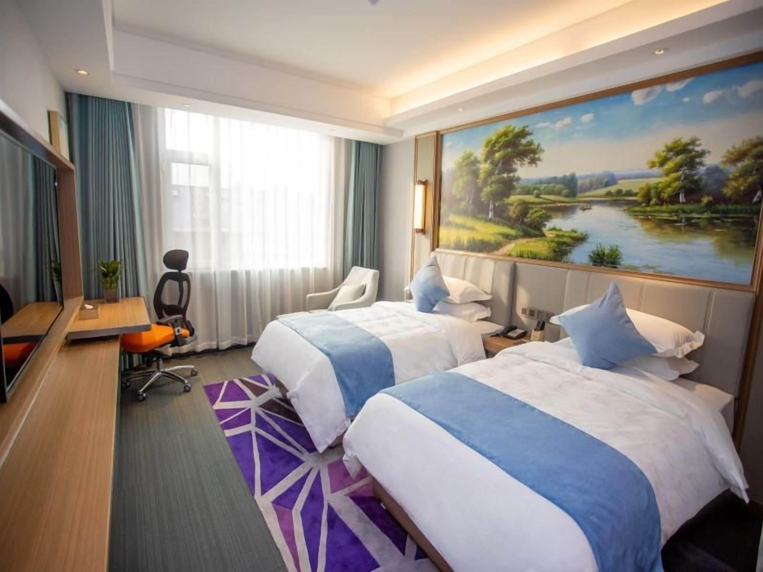 A hotel room with two beds, a desk, a chair, a painting of a landscape, and a view of a lake.