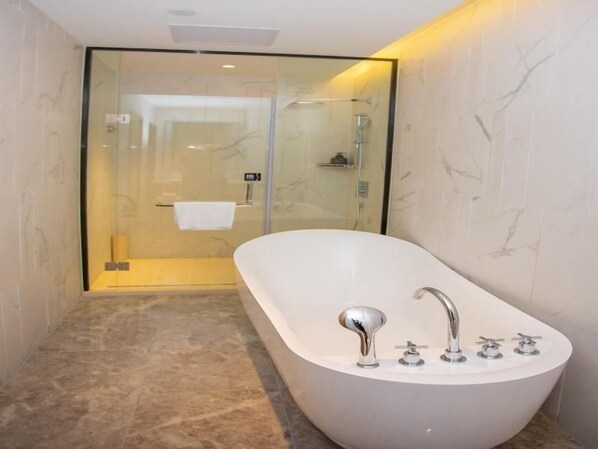 A modern bathroom with a freestanding bathtub, a glass-enclosed shower, and a marble-tiled floor.